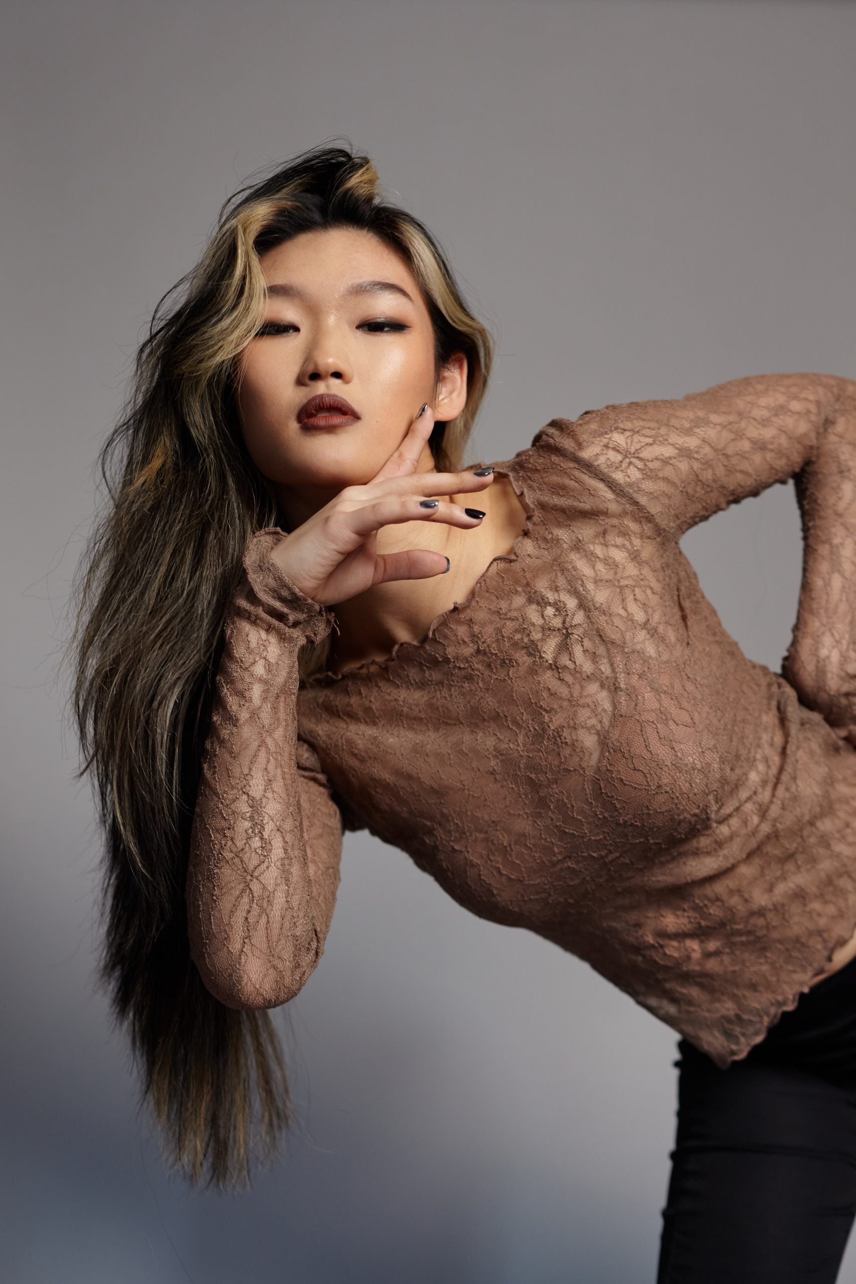 Ceci Sun - Woman wearing a textured brown sweater against a gray background